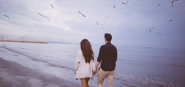 istock Young romantic couple walking on the beach, holding hands 649164028
