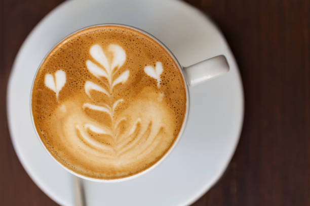 istock A cup of coffee with heart pattern in a white cup on wooden background 649179028