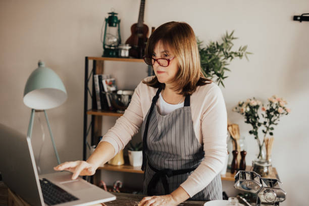 istock Woman with apron in kitchen using laptop 649188166