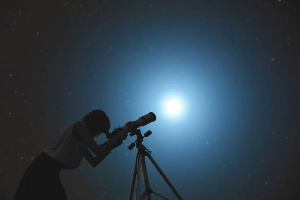 istock Girl looking at the stars through a telescope. 649188828