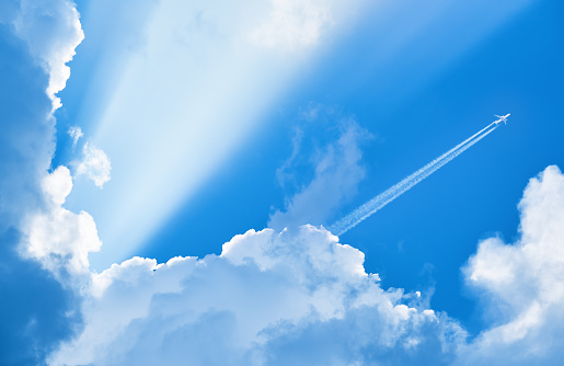 Avión que volaba en el cielo azul entre las nubes y la luz del sol photo