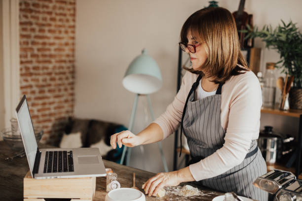 istock Mature woman in kitchen using laptop for online recipe 649205716