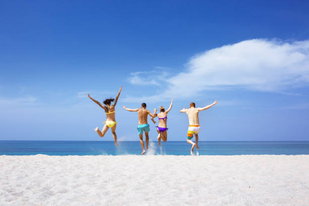 Happy friends on lonely beach Happy friends having fun on lonely tropical beach jumping teenager fun group of people stock pictures, royalty-free photos & images