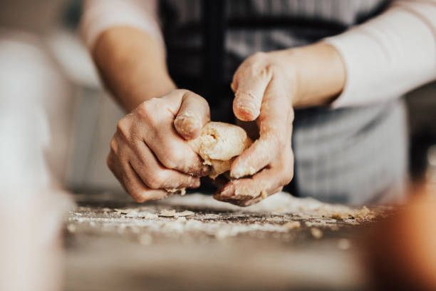 крупным планом женские руки замешиваю�т тесто - пекарь стоковые фото и изображения