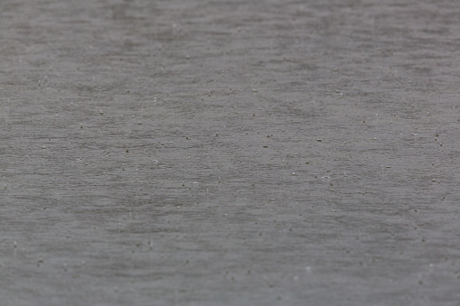 Gray water surface in rain with drops and circles