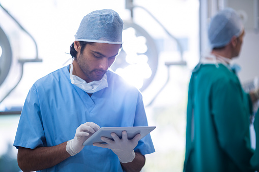 Surgeon using digital tablet in operation room at hospital