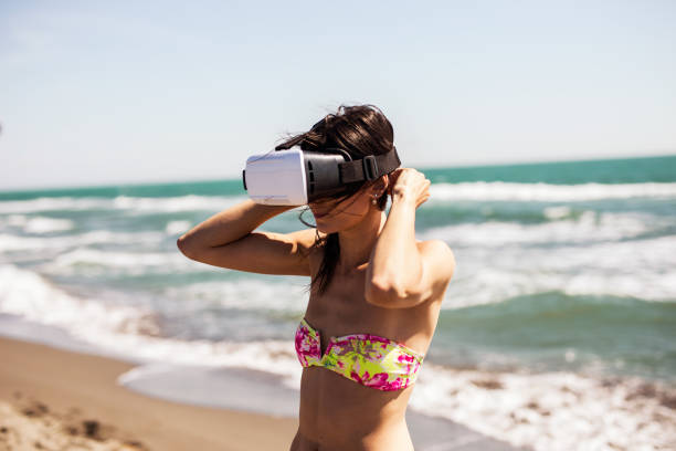 istock Beautiful brunette wearing VR on the beach 649233532
