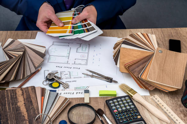 istock Man architect draws a house plan with color palette for  furniture, work tools. 649235790