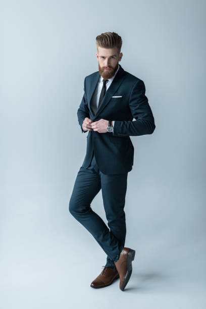 istock Handsome bearded businessman in trendy suit posing on grey 649236242