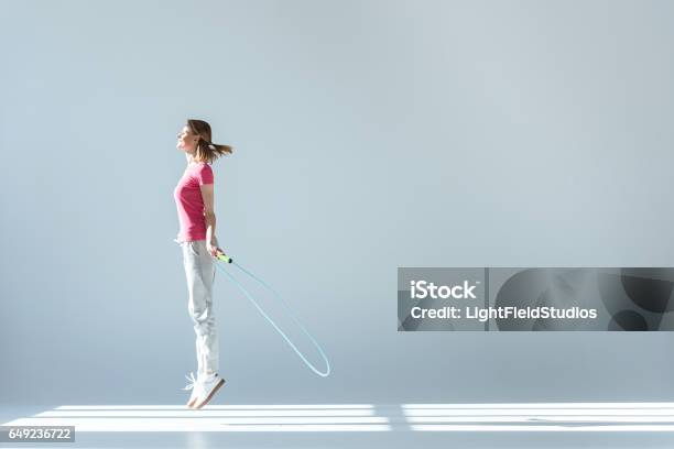 Sporty Woman Exercising With Skipping Rope On Grey Stock Photo - Download Image Now - Jumping Rope, One Woman Only, Jump Rope