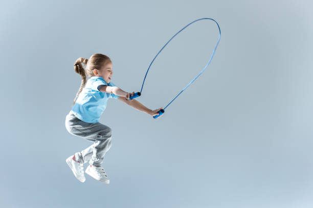 ragazza felice gobba esercizio con saltare corda su grigio - corda per saltare foto e immagini stock