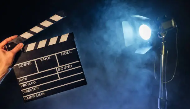 Operator holding clapperboard, studio light with claps on background. Filmmaker background