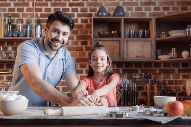 istock 'Happy father and daughter kneading dough and smiling at camera 649267856