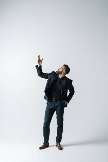 istock stylish bearded man in elegant suit with hand up 649273846