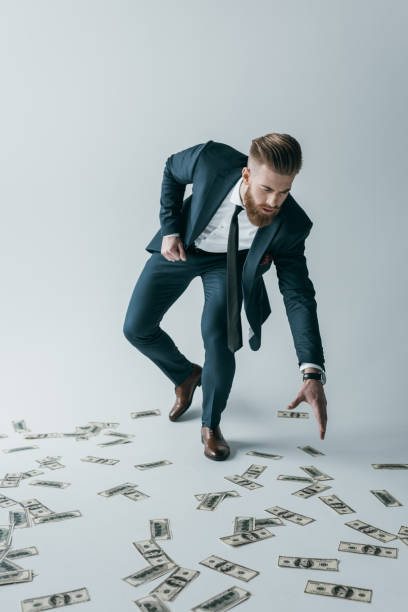 istock stylish businessman picking up dollar banknotes on grey 649273914