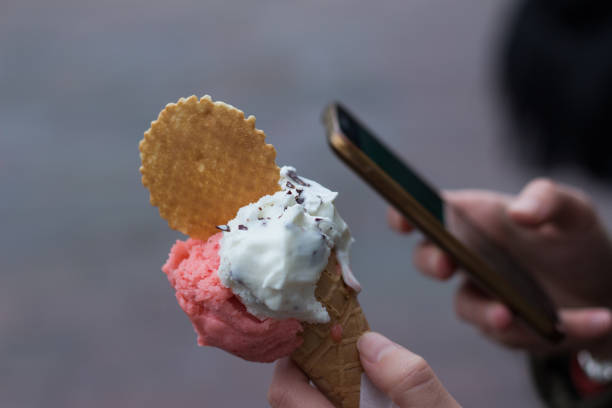 istock Person using the cellphone, holding ice-cream on a blurred background 649278766