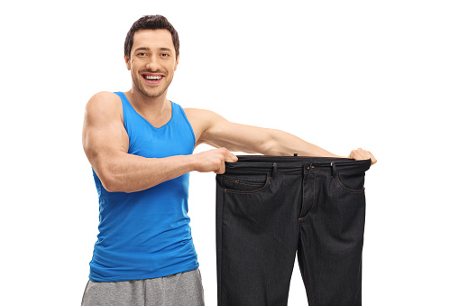 Happy man holding a pair of oversized pants isolated on white background