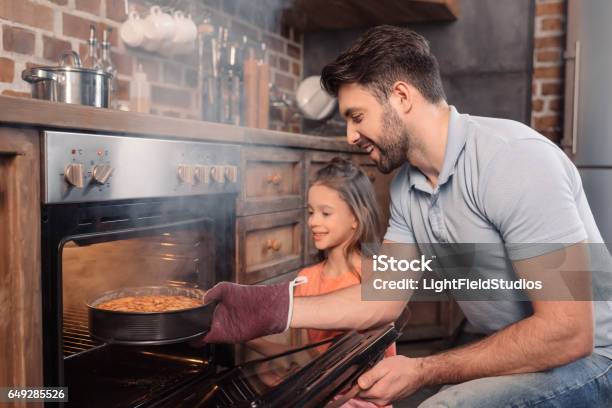 Smiling Father And Daughter Taking Cake From Oven Stock Photo - Download Image Now - Oven, Steam, Father