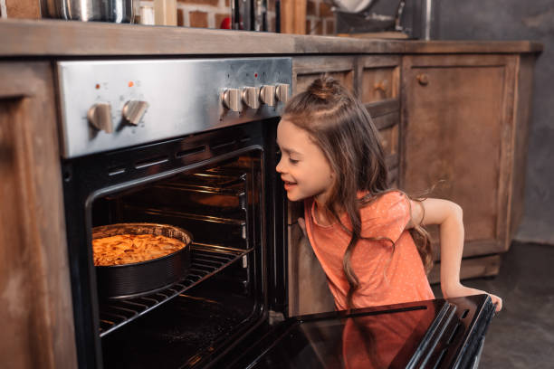 istock smiling girl looking at cake in oven in kitchen 649286256