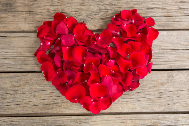 istock Red rose petals scattered on wooden background 649289742