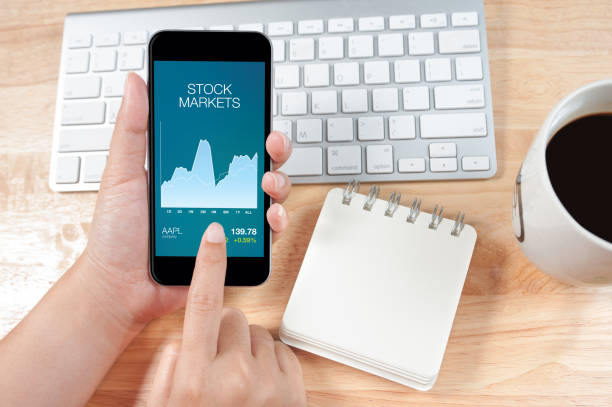 istock Woman using the phone with stock market screen 649289920