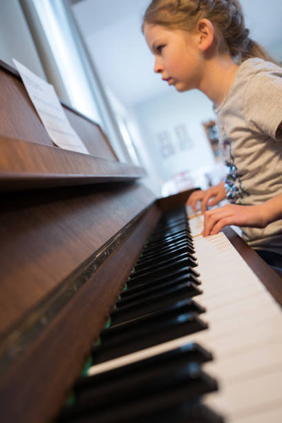 istock Girl reading notes and playing the piano 649298906