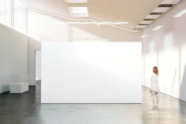 Woman walking near blank white wall mockup in modern gallery Woman walking near blank white wall mockup in modern gallery. Girl admires a clear big stand mock up in museum with contemporary art exhibitions. Large hall interior, banner exposition show corridor photos stock pictures, royalty-free photos & images