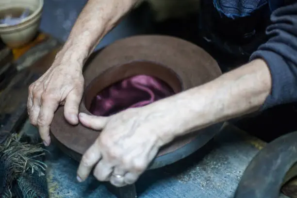Close up shot of a hatter's hands, manufacturing a hat.