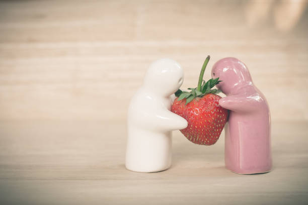 jouets en céramique donnant une fraise au couple pour leur amour - suçon photos photos et images de collection
