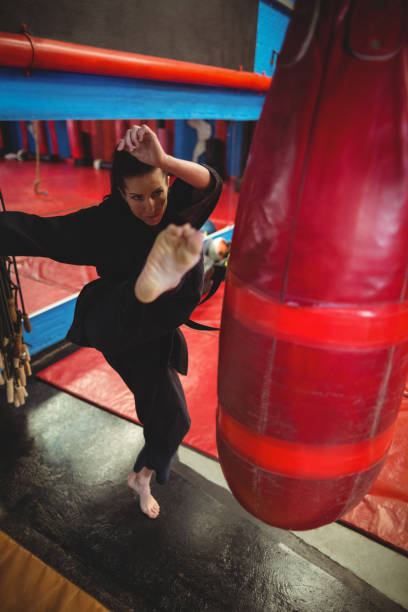 joueur de karaté féminin pratiquant de boxe avec sac de boxe - karate punching bag caucasian leisure activity photos et images de collection