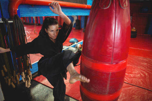joueur de karaté féminin pratiquant de boxe avec sac de boxe - karate punching bag caucasian leisure activity photos et images de collection