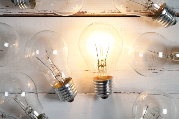 istock Vintage incandescent bulbs on white wooden table 649309490