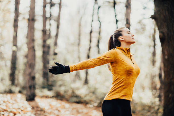 Happy casual man breathing fresh air in a park with trees in the background
