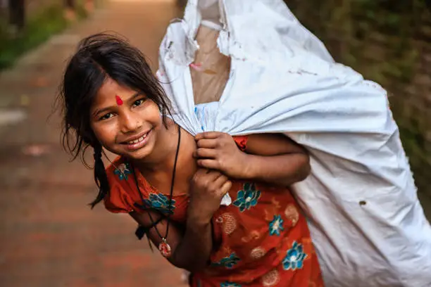 Photo of Poor Indian girl collecting plastic bottles for recycling