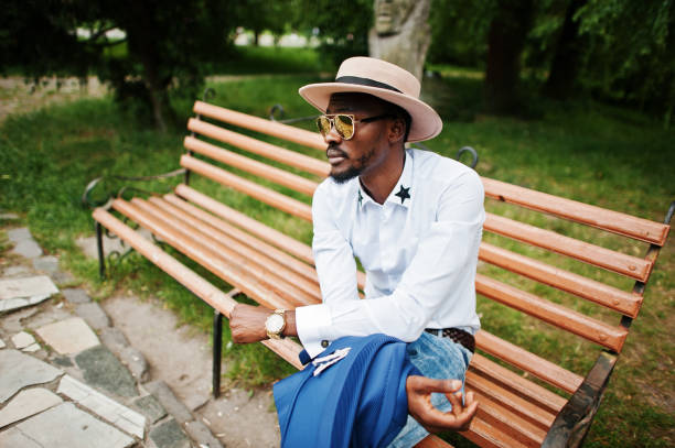 istock Rich black man sitting on bench at golden sunglasses and hat 649332500