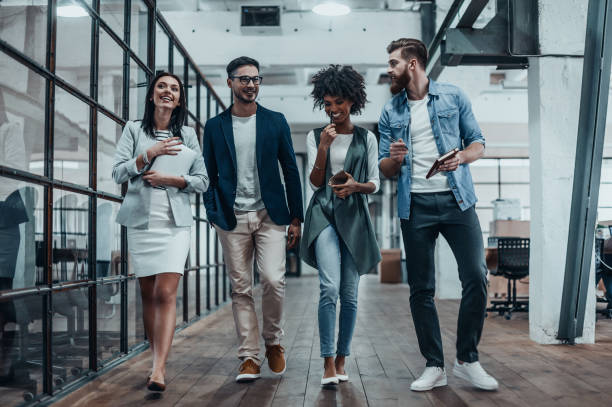 Sharing business experience. Full length of young modern people in smart casual wear having a discussion while walking through the large modern office smart casual stock pictures, royalty-free photos & images