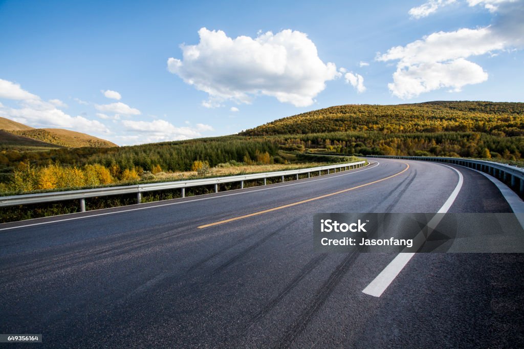 mountain road This is a road through the grasslands,And beautiful mountains,clouds,Changing light. Road Stock Photo