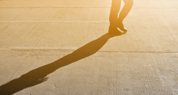 道路上の影と日光で歩いたり踏んだりする男のシルエット。 - businessman walking shadow focus on shadow ストックフォトと画像