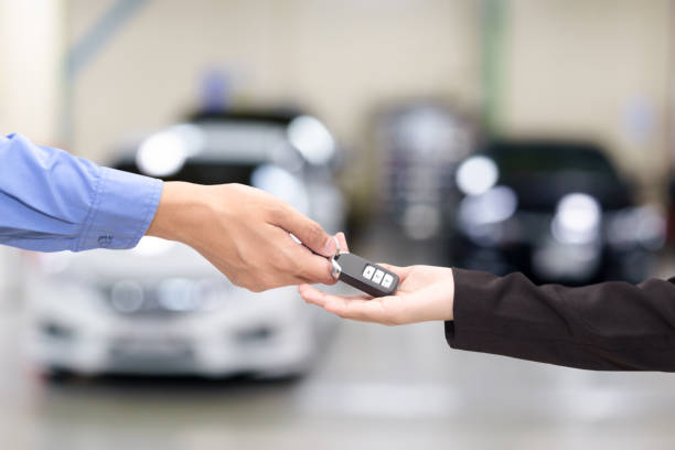 Young business women giving a key car in font of car. stock photo