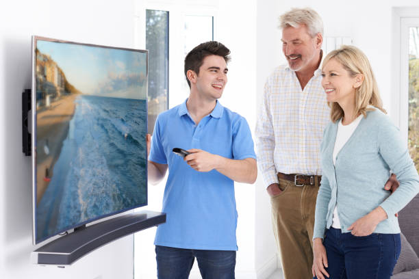 Man Demonstrating New Television To Mature Couple At Home Man Demonstrating New Television To Mature Couple At Home installing tv stock pictures, royalty-free photos & images