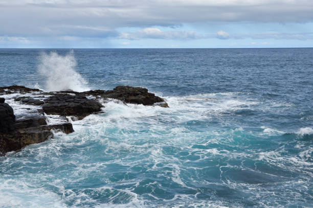 istock Waves against a cliff with blue sea in background 649373802