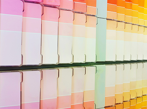 Rows of paint swatches showing varied pastel colour tones in shades of pink and peach in a paint or hardware store.