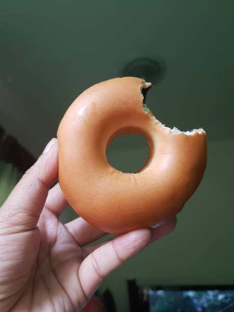 istock Man's hand hold a bited chocolate donut in the room 649380016