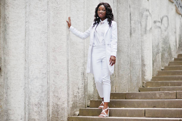 istock Young african american girl, dressed in white, background white stone wall 649380700