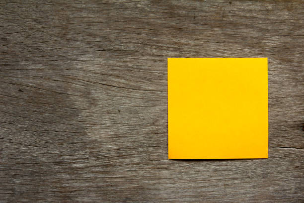 Blank orange note paper attach on brown wooden background for memo or remind