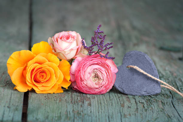 Flower decoration with a heart from slate for a little message on an old shabby wooden table for mothers day