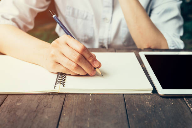 istock Woman hand with pencil writing on notebook at coffee shop. 649391956
