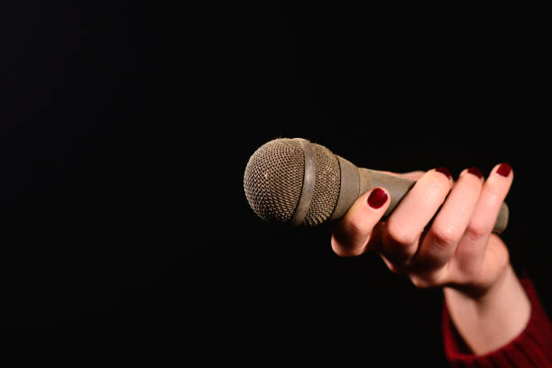 istock woman hands holding dirty and dusty microphone on a dark background 649417486