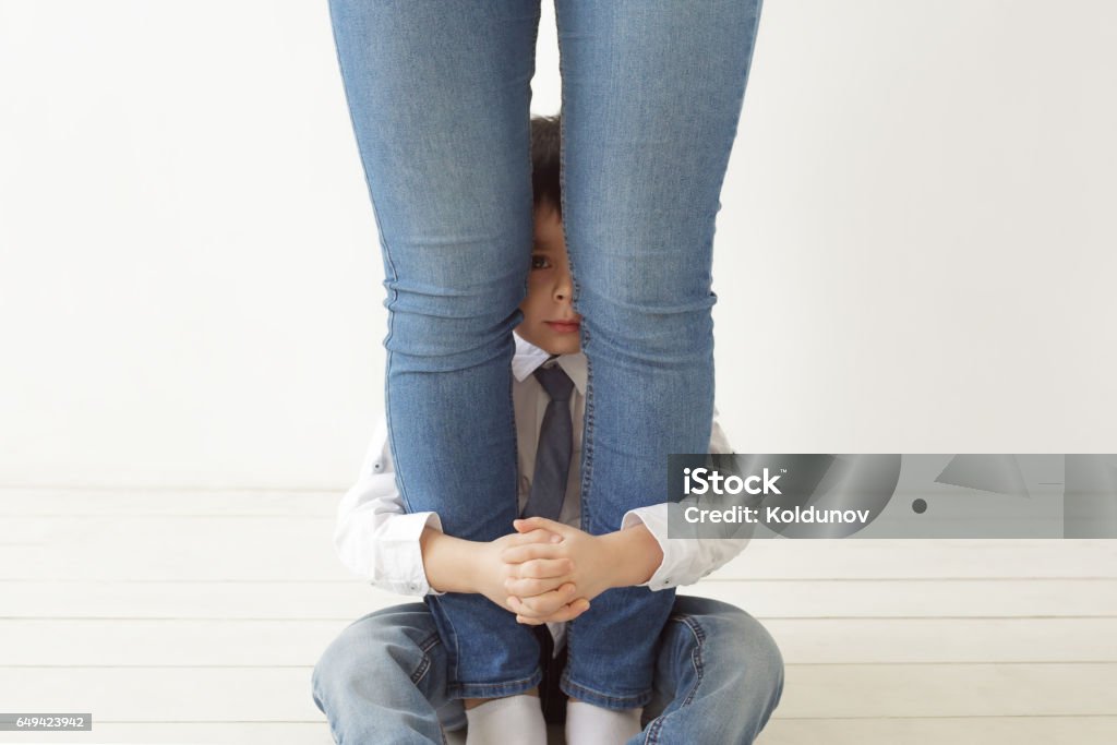 Defend and hold the child out of trouble The boy hugs mom's legs, playing hide and seek. Child Stock Photo