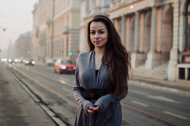 Young girl posing outside, looking posing on the street with a smile in sunny day golden at hour time, girl walking on the empty way with sunlight.